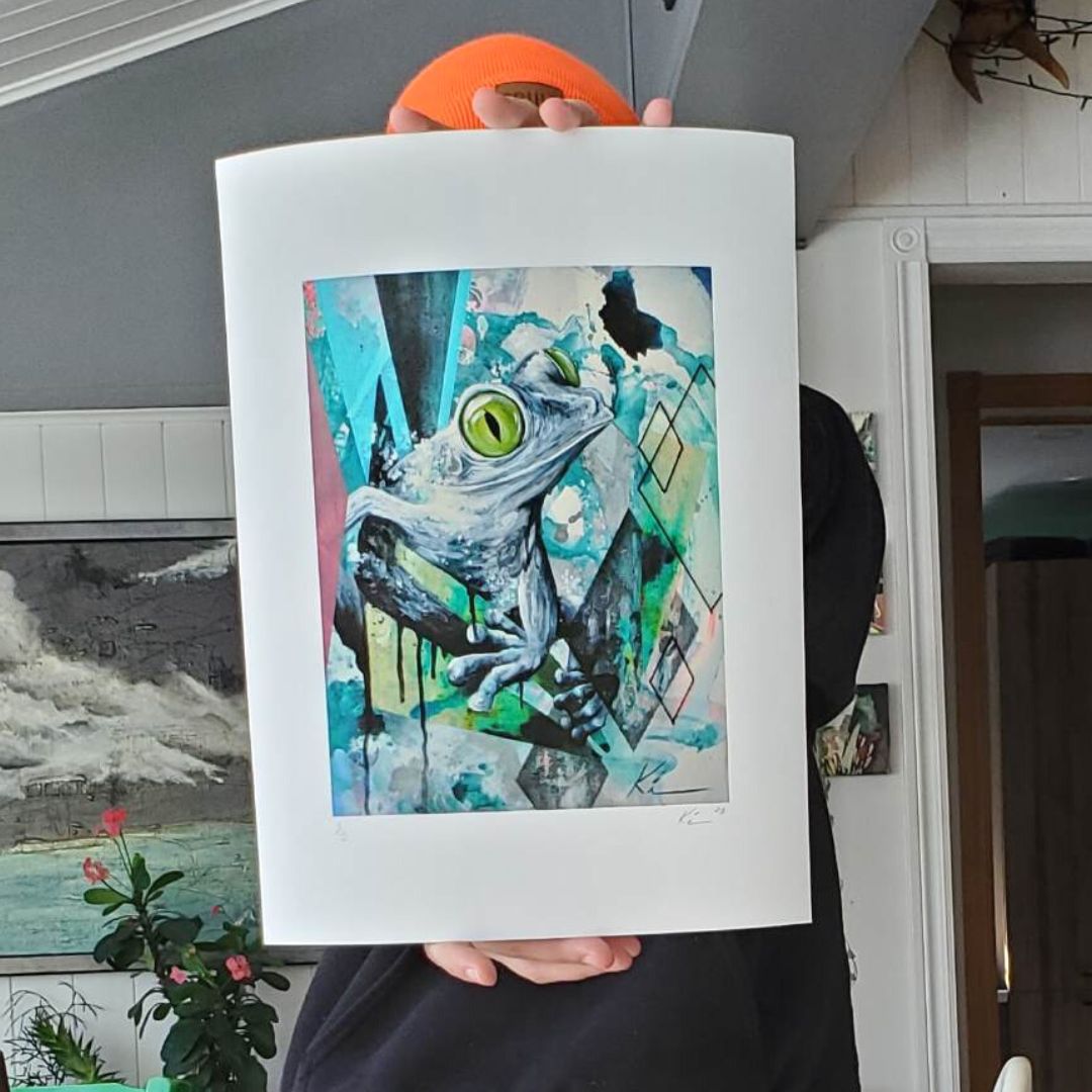 artiste tenant une reproduction de son oeuvre illustrant une grenouille